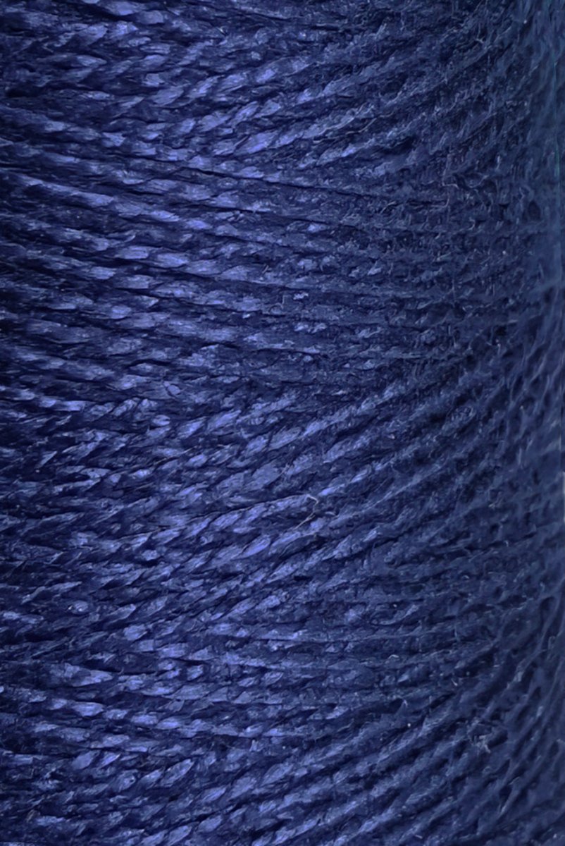 Close-up of tightly wound dark blue Circulo 5/2 Looma Mercerized Pearl Cotton Yarn on a large cone, showing detailed texture and fibers with light reflecting on its surface and the strands running diagonally across the image.