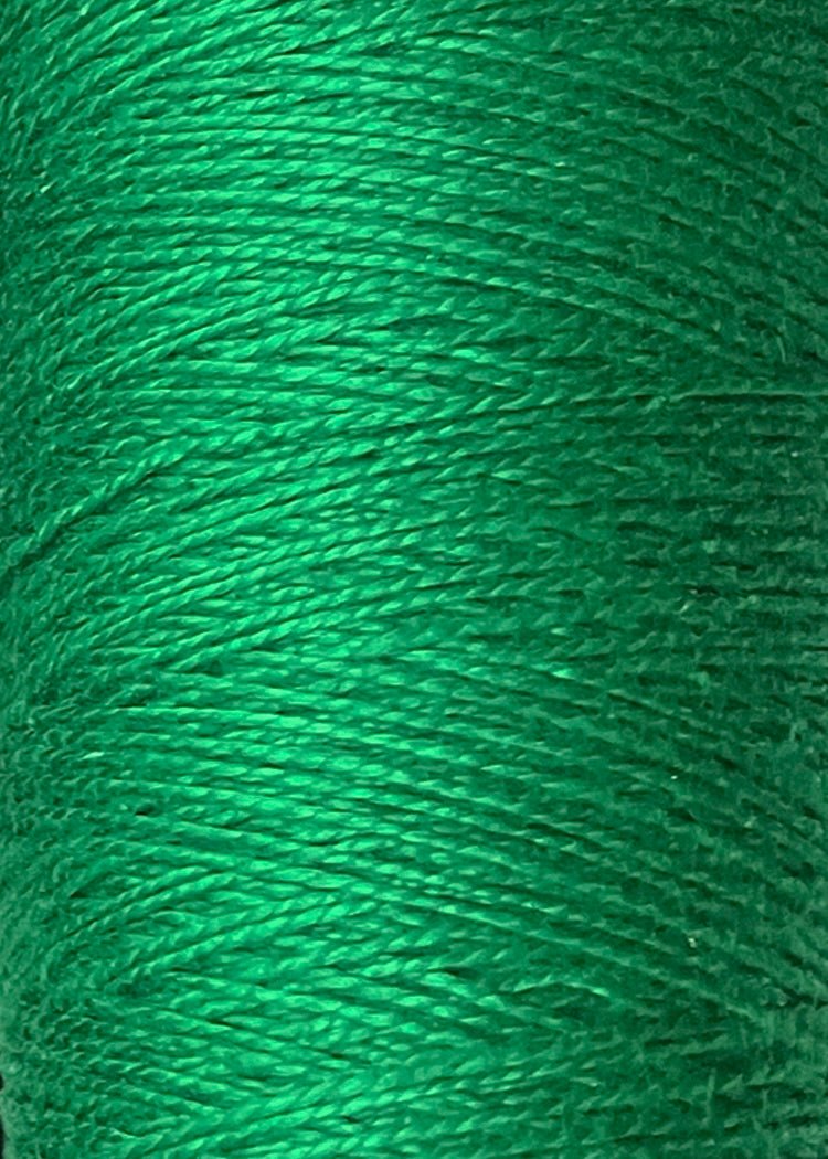 Close-up of vibrant green Circulo 10/2 Looma Mercerized Pearl Cotton Yarn, tightly wound on a mini cone, highlighting its smooth texture and visible individual fibers.