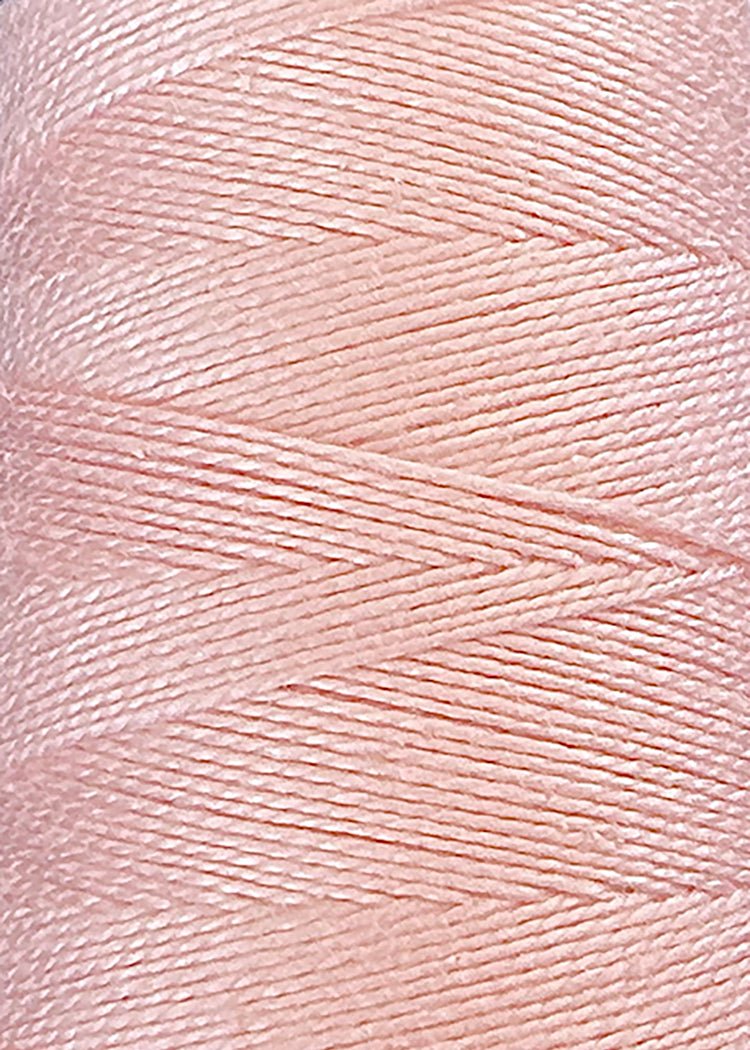 Close-up of a spool of Circulo 3/2 Looma Mercerized Pearl Cotton Yarn in light pink, tightly wound on a mini cone with visible texture and a diagonal layering pattern.