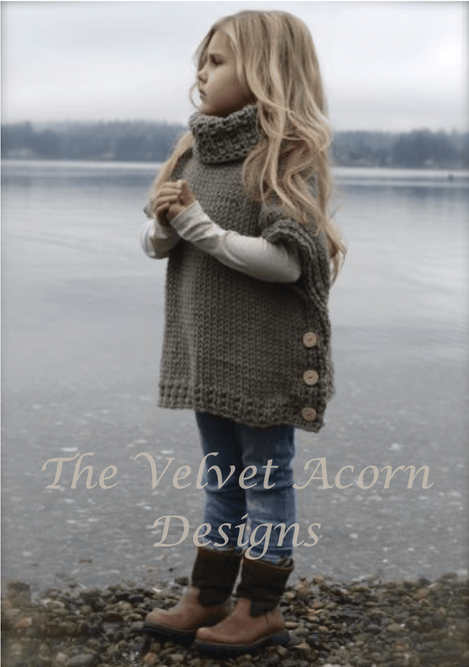 A young child stands near a body of water wearing a chunky knit Azel Pullover Pattern by Heidi May with a high collar and side buttons.