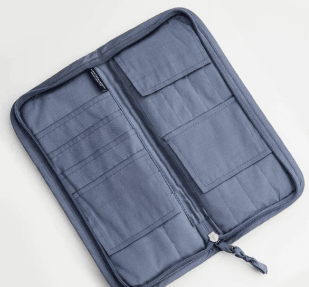 The Lantern Moon Interchangeable Needle Case by Bryson Distributing, Inc. is a blue IKAT fabric zippered organizer with multiple pockets and slots on both sides, shown open on a white surface.