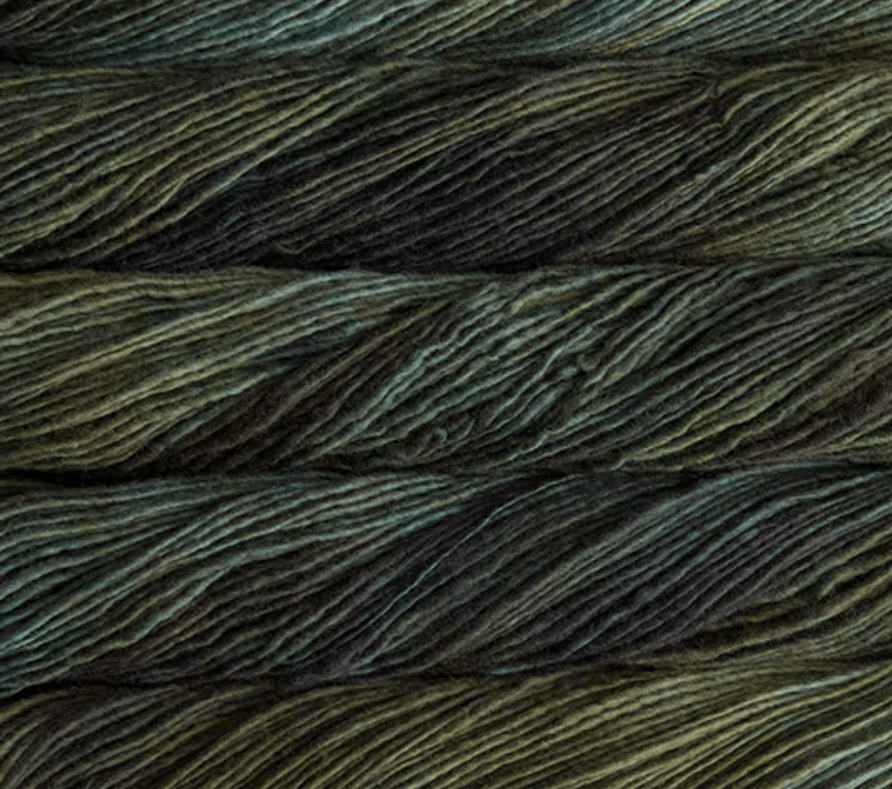 Close-up of Malabrigo Merino Worsted Wool Yarn in variegated shades of dark green, black, and hints of brown.