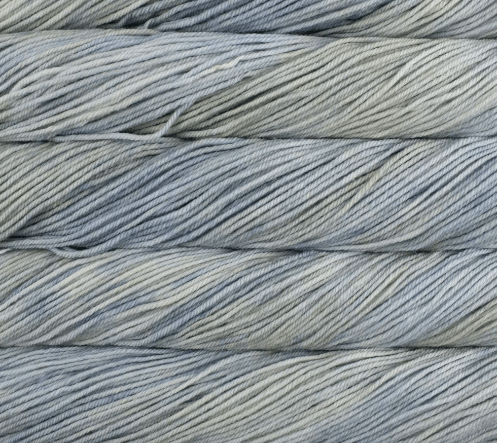 Four stacked hanks of kettle-dyed, variegated Malabrigo Rios yarn in shades of light blue, grey, and soft green.