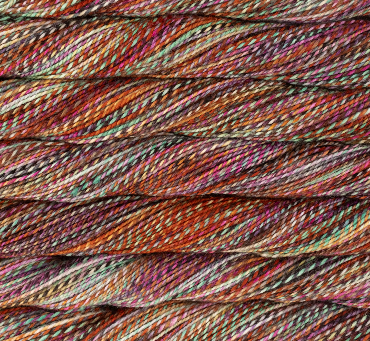 Close-up of Malabrigo Torzal sport weight yarn featuring a multi-ply, variegated blend of orange, teal, purple, and cream fibers twisted together.