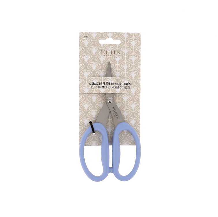 A pair of 6.75" Micro-Serated High-Precision Scissors by Bryson Distributing, Inc., featuring light blue handles, shown in its packaging against a patterned beige background.