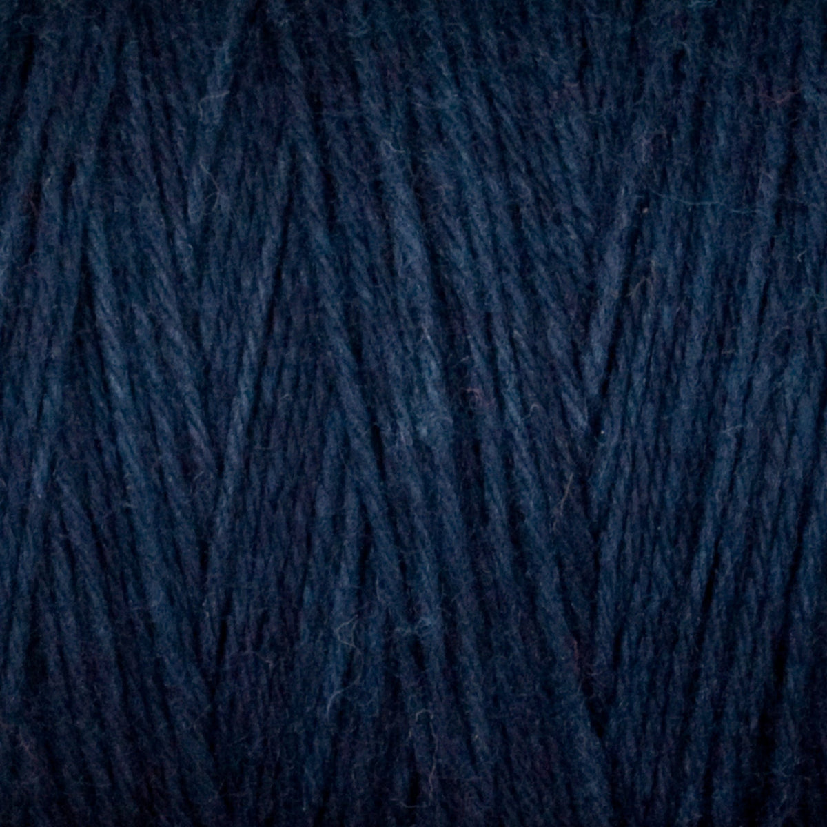 Close-up of dark blue Cotton Carpet Warp 8/4 fibers by Great Northern Weaving, highlighting the tightly woven, colorfast 4-ply cotton yarn texture and strand details.
