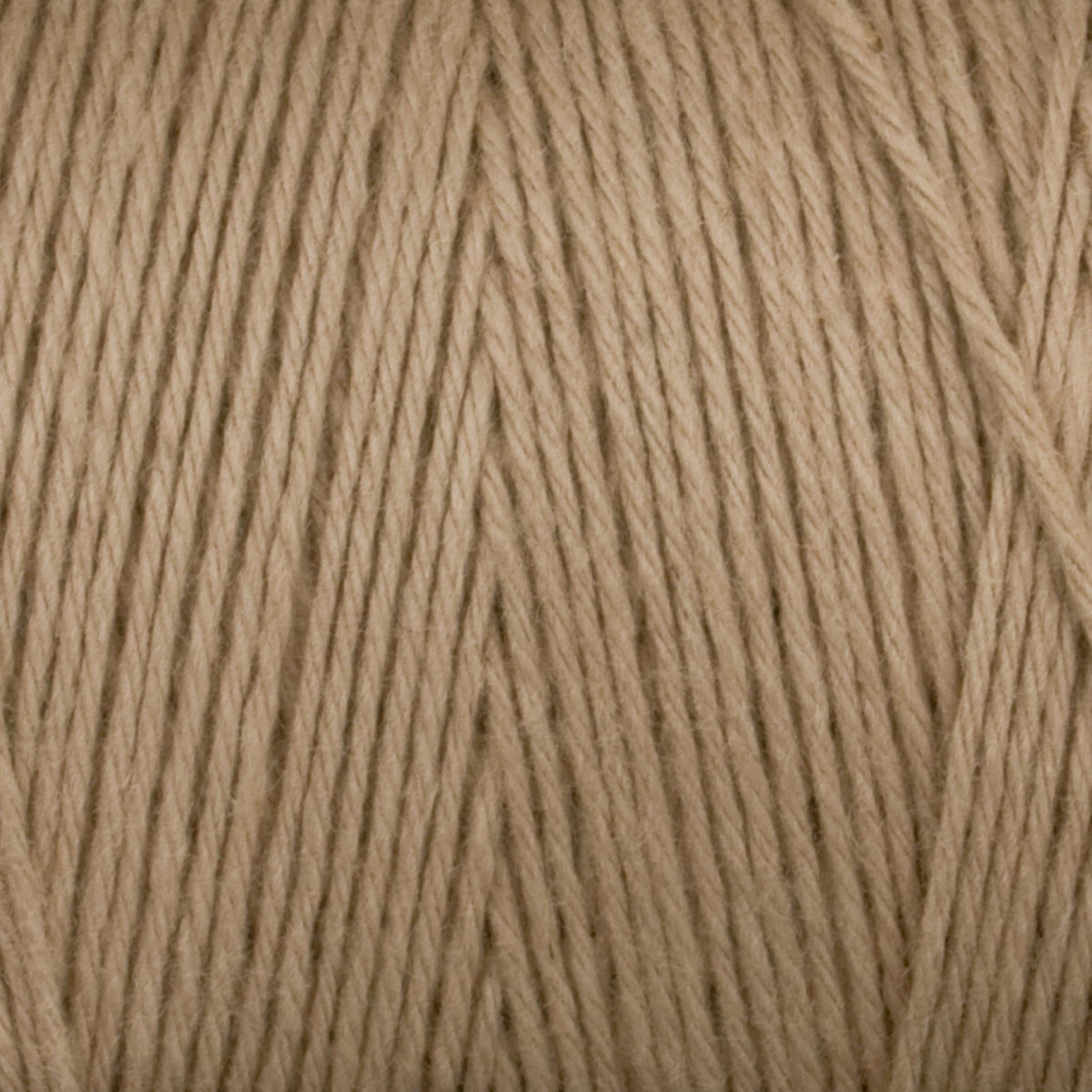 Close-up of Great Northern Weaving's Cotton Carpet Warp 8/4 in beige, featuring tightly wound 4-ply cotton strands and textured fibers—perfect for creating durable, colorfast rugs.