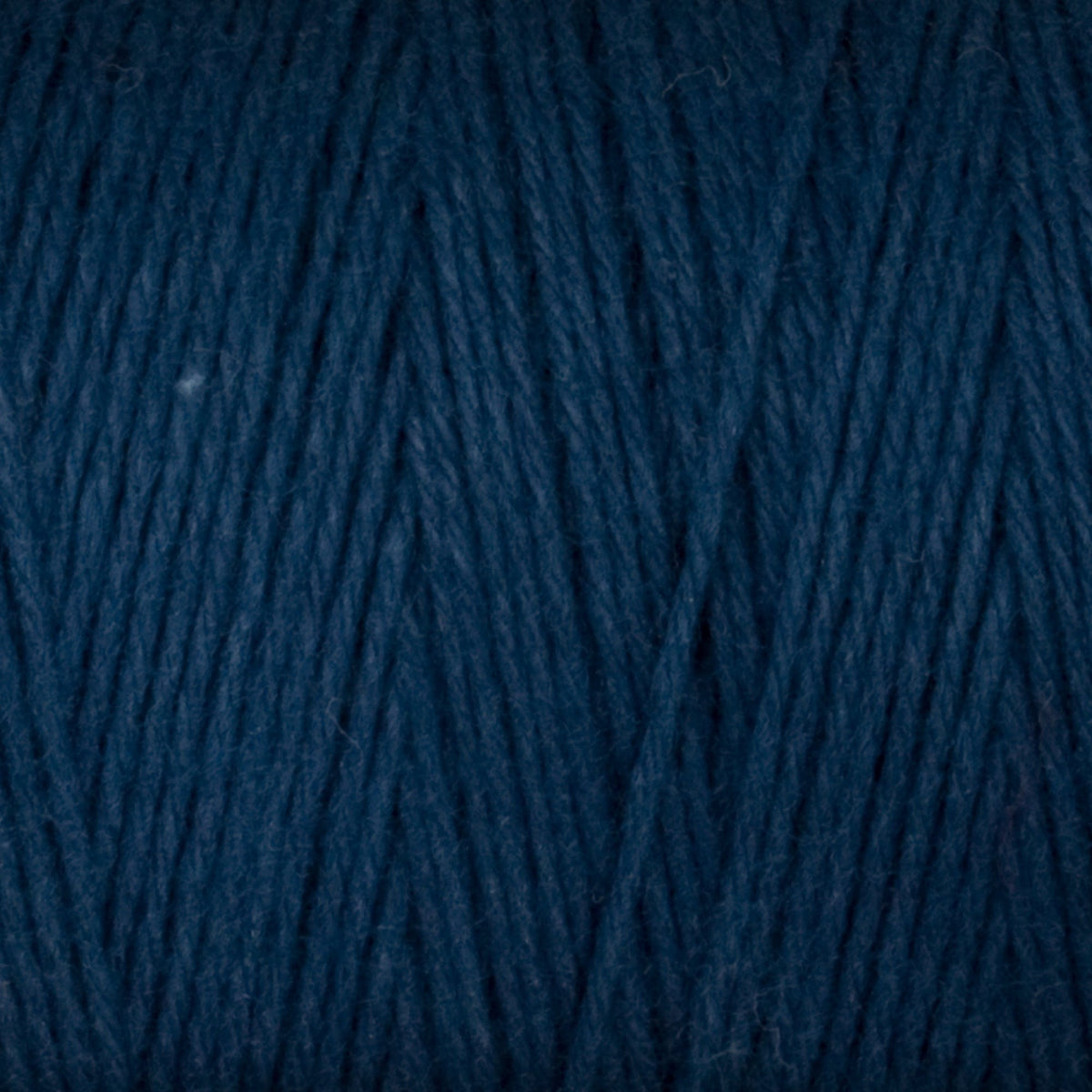 Close-up of Great Northern Weaving's Cotton Carpet Warp 8/4 in dark blue, featuring tightly wound 4-ply cotton fibers and textured strands ideal for rug making.