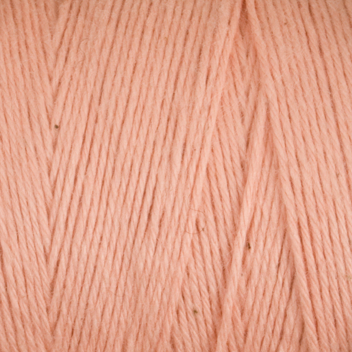 Close-up of peach-colored Cotton Carpet Warp 8/4 by Great Northern Weaving, showing smooth, intertwined 4-ply cotton strands running diagonally and highlighting the soft, colorfast fibers and detailed texture of this yarn.