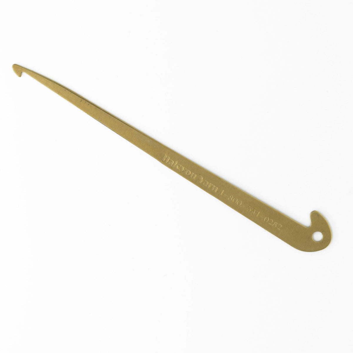 The Halcyon Yarn Engraved Brass Hook for Threading and Sleying is a gold-colored, double-hook tool engraved with text and a phone number—a must-have addition to any weaver’s toolkit, shown on a white background.