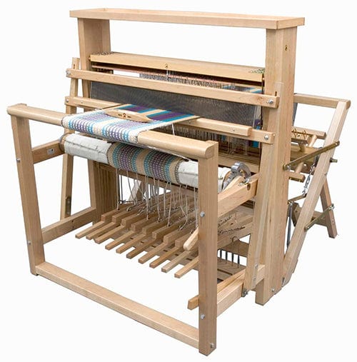 The Leclerc Nilus II 8-Shaft Floor Loom by Leclerc Looms, a jack loom with back-hinge treadles, is shown in use, partially threaded with colorful woven fabric.