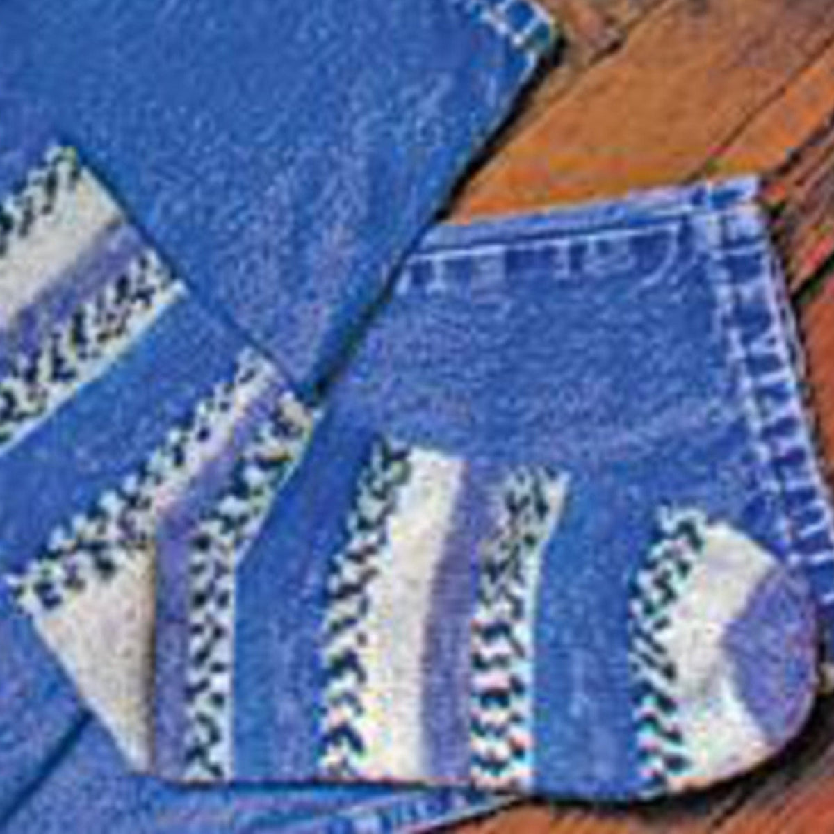 A pair of socks made with Lisa's Knits Basic Toe-Up Sock Pattern (8 st/Inch) in blue and white rests on wood beside blue denim.
