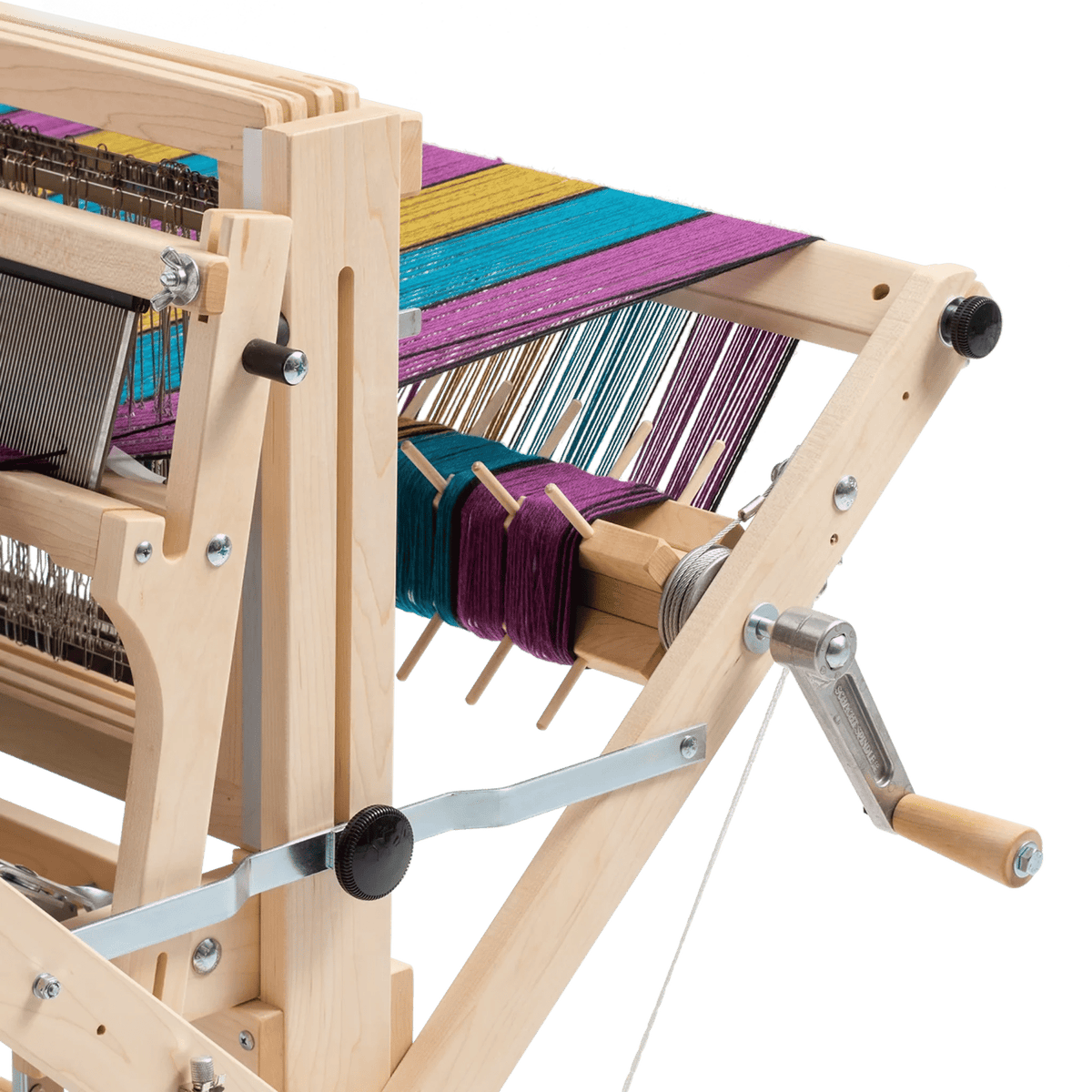 A close-up of a Schacht Spindle Co. Wolf loom fitted with the Schacht Sectional Warp Beam (temporarily out of stock), features vibrant yellow, blue, and purple threads stretched across its frame and a hand crank on the side.