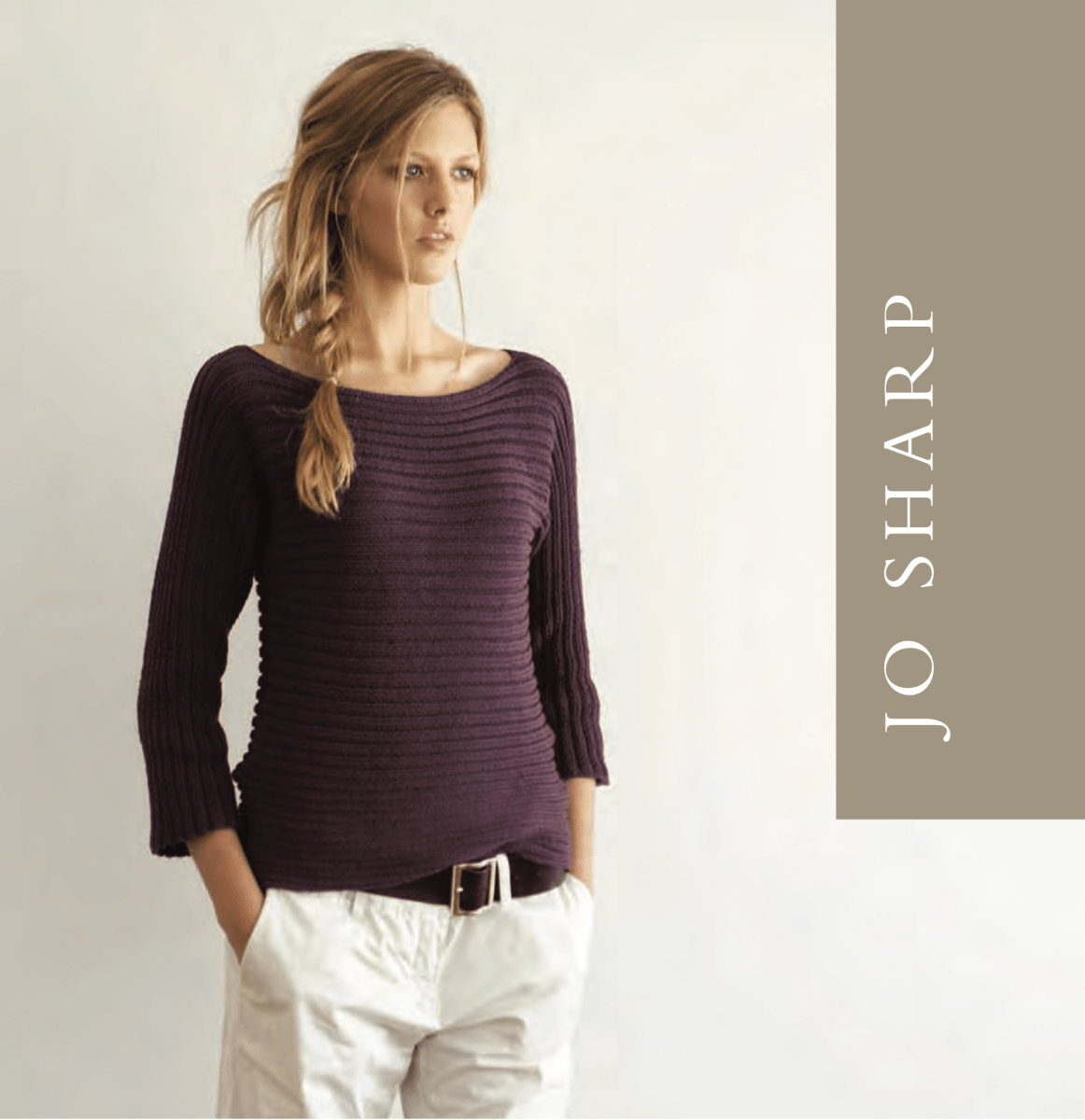 A woman wearing a dark purple, horizontally ribbed Sideways Ribbed Top Pattern boat-neck top with three-quarter sleeves and white trousers.