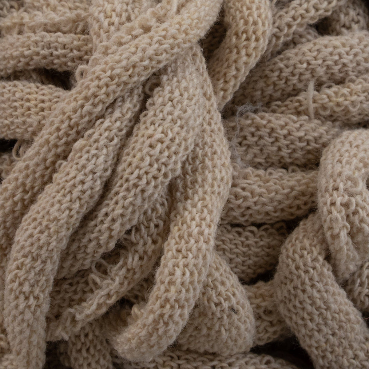 Close-up of tangled, cream-colored Harrisville Potholder Loops by Friendly Loom with a soft, textured pattern reminiscent of cotton loops. The loops appear dense and thick, showcasing intricate knitwork akin to that crafted on a traditional loom.