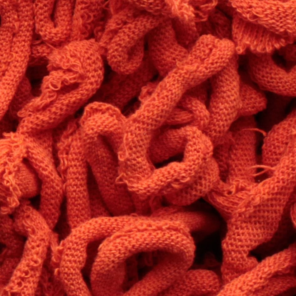 Close-up of the Harrisville Potholder Loops - Traditional Size by Friendly Loom, featuring a textured surface composed of intertwined, looped strands of vibrant orange fabric that resemble intricate patterns from a traditional loom, resulting in a dense and tangled appearance.