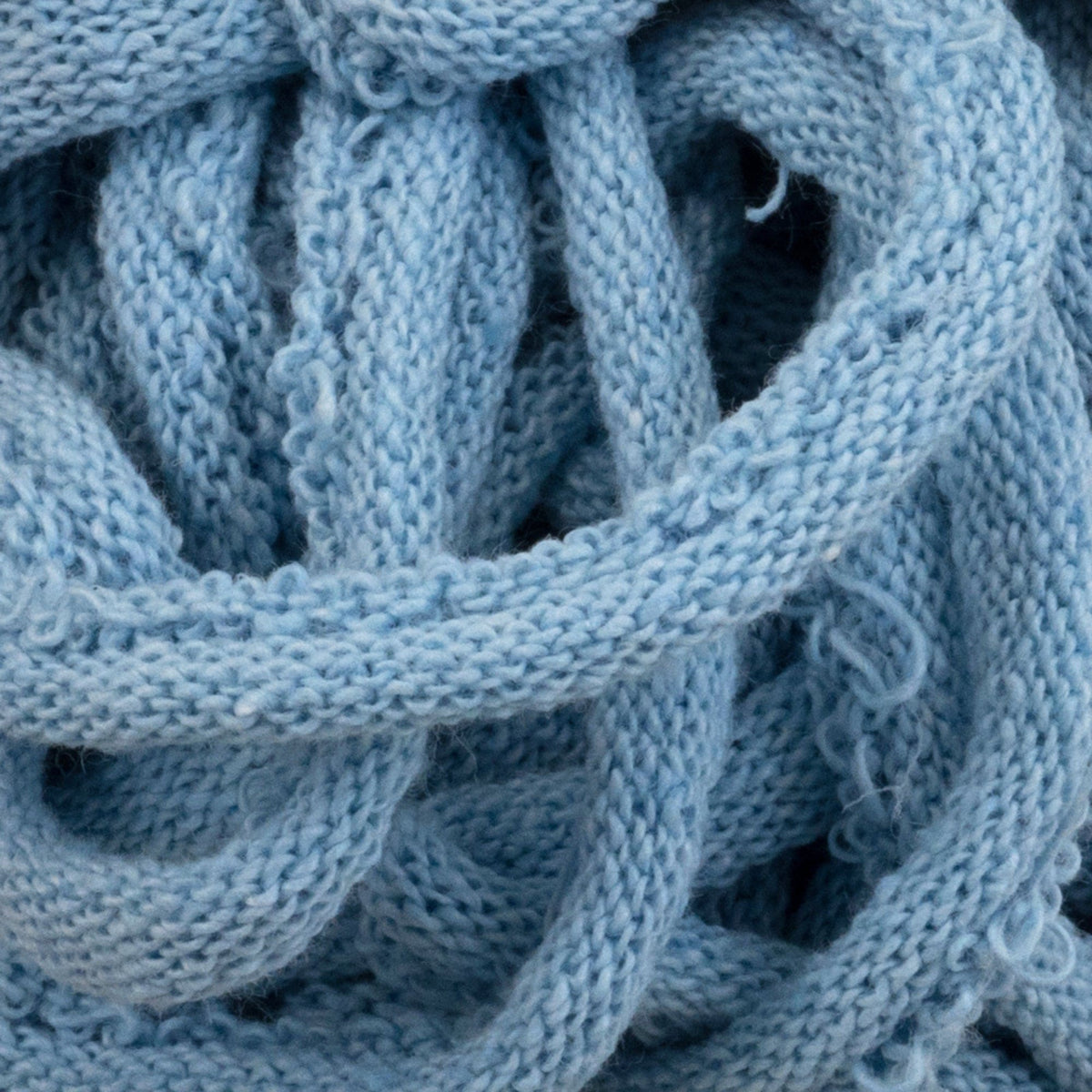 A close-up of the Harrisville Potholder Loops - Traditional Size by Friendly Loom, revealing its soft, light blue knitted fabric intricately looped and tangled like cotton loops on a traditional loom, elegantly showcasing its detailed texture.