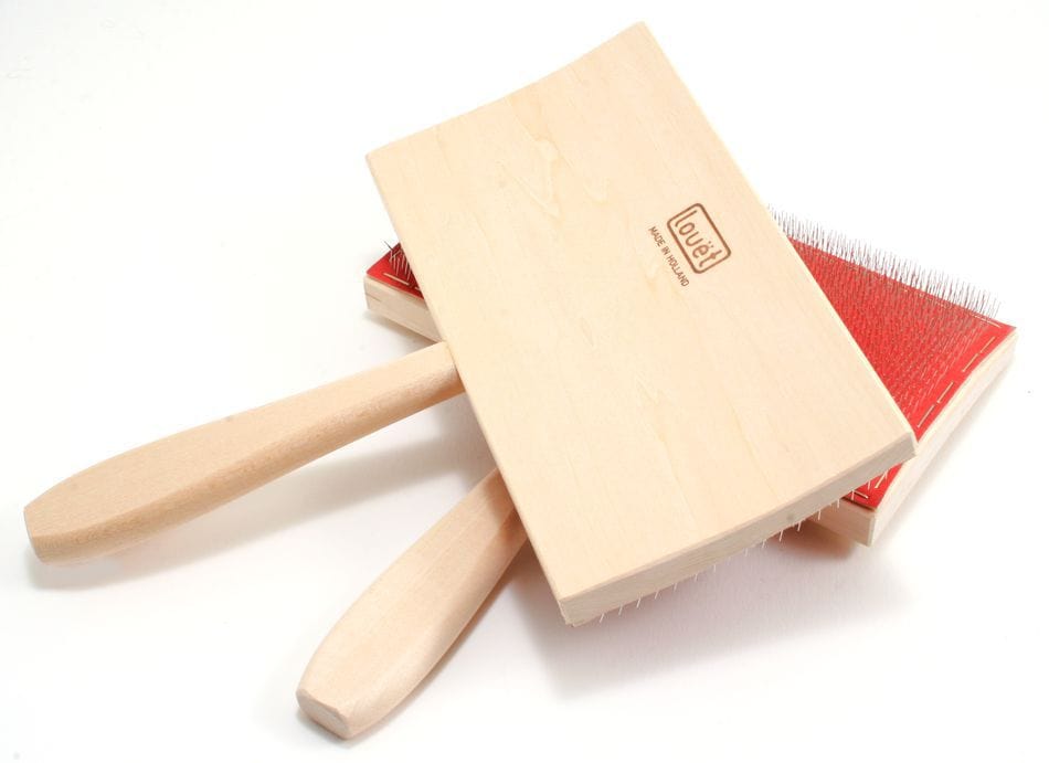 A pair of Louët Cotton Carders by Louet Inc., measuring 7½"x4" with wooden handles and red cloth surfaces featuring 110 tpi, lie delicately crossed on a white background.