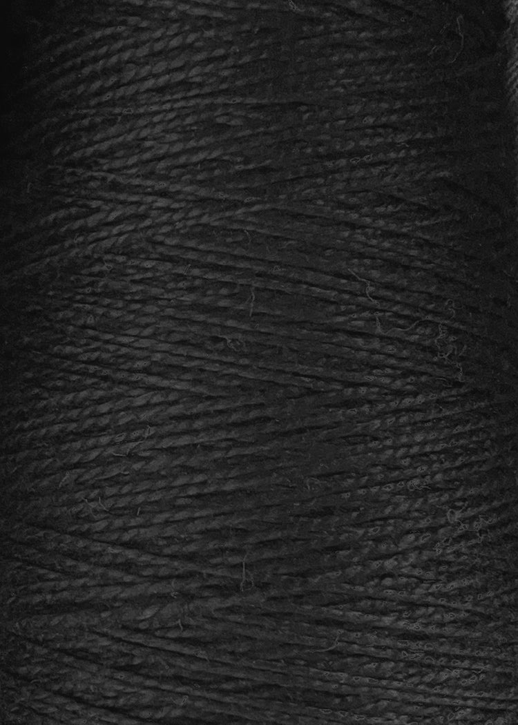 Close-up view of tightly wound Circulo 10/2 Looma Mercerized Pearl Cotton Yarn on a large cone, highlighting the texture and fine fibers of this black material.