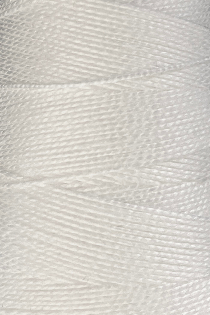 Close-up of a large cone of Circulo 5/2 Looma Mercerized Pearl Cotton Yarn, showcasing its tightly wound, shiny white fibers in vivid detail—crafted from Oeko-Tex certified cotton for lasting quality.