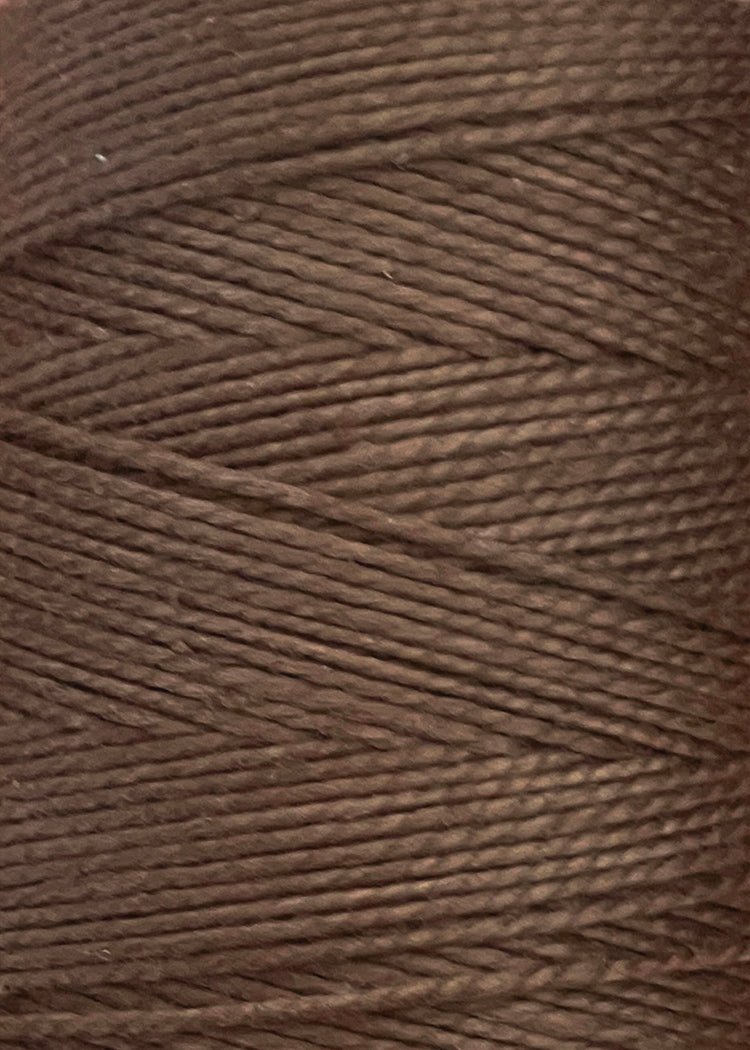 Close-up of a spool of brown thread, displaying tightly wound strands and a textured surface. The Circulo 10/2 Looma Mercerized Pearl Cotton Yarn | Mini Cone is made from 100% cotton and Oeko-Tex certified, ensuring both quality and safety for your crafting projects.