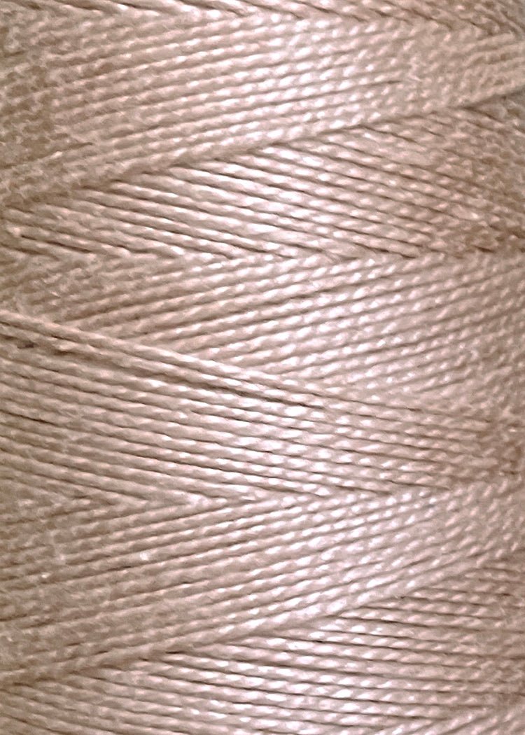 Close-up of a large cone of Circulo 3/2 Looma Circulo Mercerized Pearl Cotton Yarn in light beige, highlighting the shiny, tightly wound fibers and textured surface.