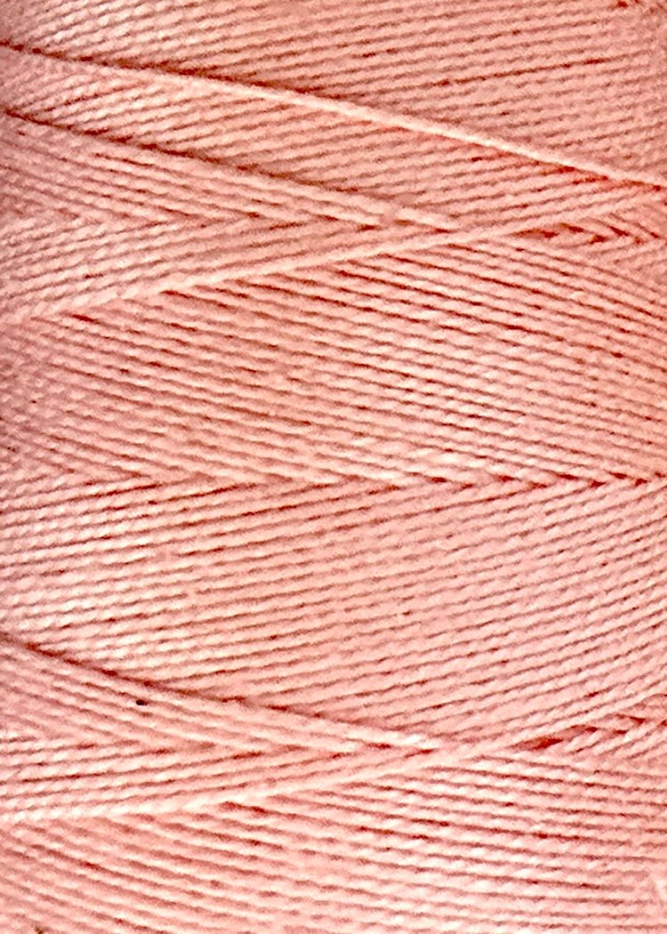 Close-up of the finely textured, light pink 3/2 Looma Circulo Mercerized Pearl Cotton Yarn by Circulo on a large cone, highlighting its neatly wound thread layers and distinct diagonal pattern.