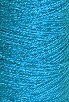 Close-up of Circulo 3/2 Looma Circulo Mercerized Pearl Cotton Yarn in teal blue, wound tightly in parallel rows on a large cone, highlighting the texture and fine fibers of the material.