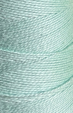 Close-up of Circulo’s 10/2 Looma Mercerized Pearl Cotton Yarn in light blue, wound tightly in parallel layers on a large cone, highlighting the smooth texture and sheen of the individual fibers.