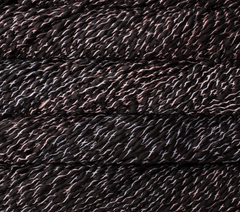Malabrigo Caracol super bulky merino wool yarn in black with a spiraling, ribbon-like texture and subtle pink and white highlights.