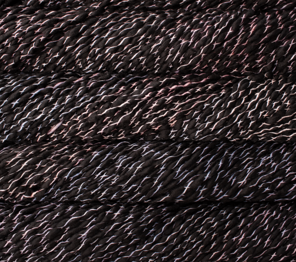 Malabrigo Caracol super bulky merino wool yarn in black with a spiraling, ribbon-like texture and subtle pink and white highlights.