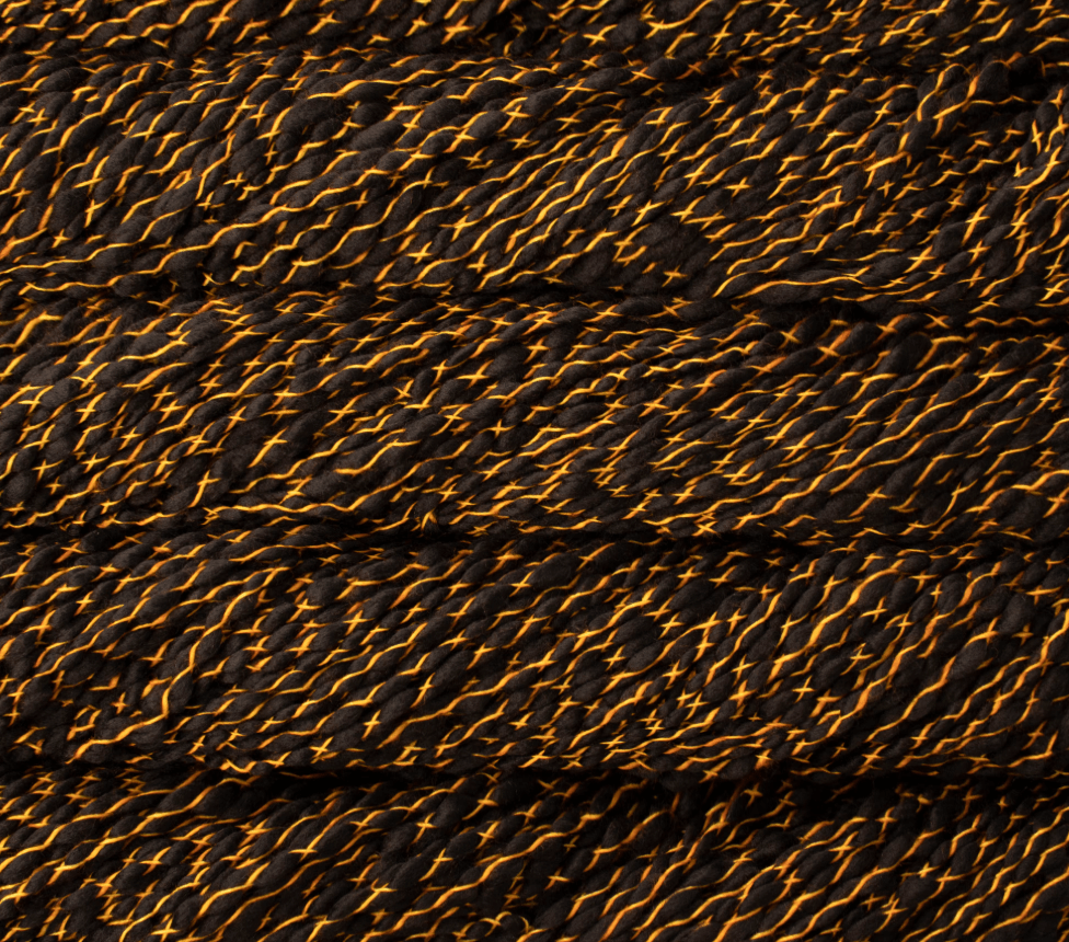Malabrigo Caracol super bulky merino wool yarn in black with thin, bright orange strands wrapped around it in a thick, textured cross-hatch pattern.