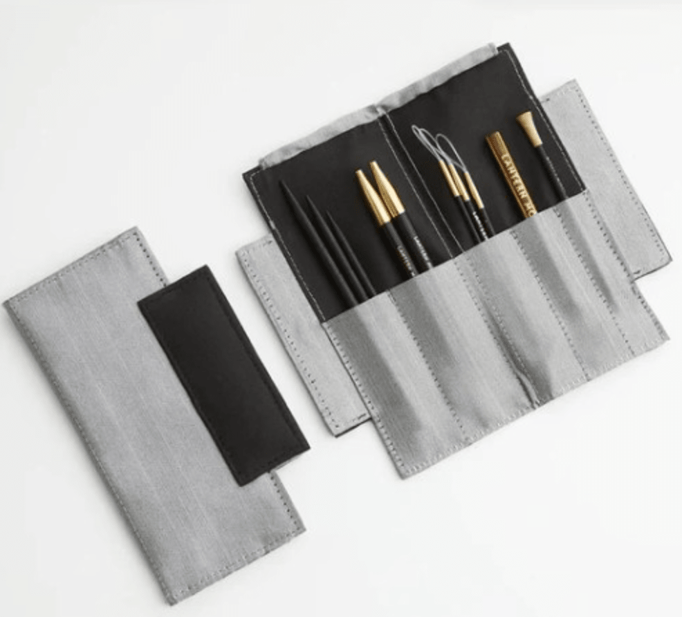 The Lantern Moon Mindy Sleeve by Bryson Distributing, Inc. is shown open with stitched compartments for organized knitting needle and crochet hook storage, and closed as a neatly folded gray fabric case with a black flap.