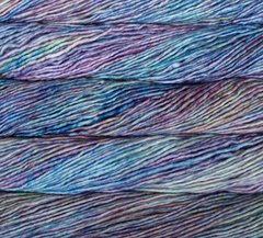 Several skeins of Malabrigo Mecha hand-dyed superwash yarn featuring a variegated pattern of purple, blue, and pale green tones.