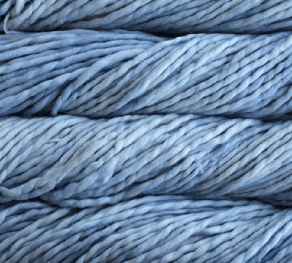 Close-up of three stacked skeins of thick, light blue, single-ply Malabrigo Rasta super bulky yarn.