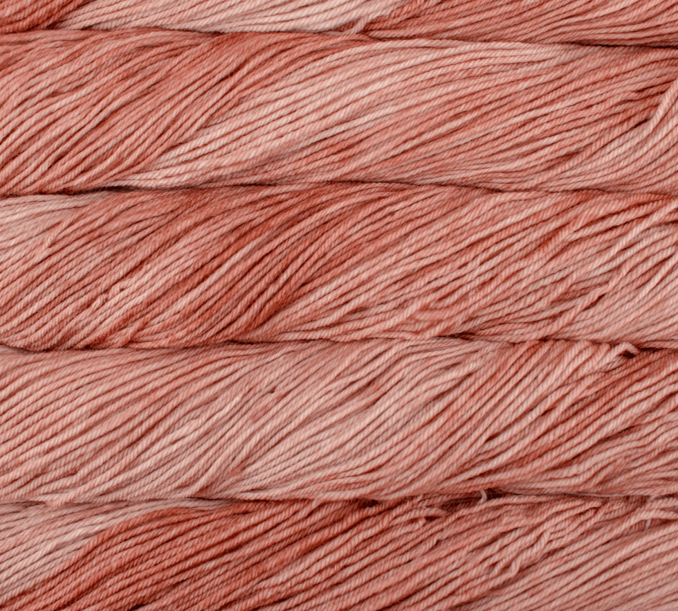 Close-up of four stacked hanks of dusty-rose Malabrigo Rios yarn.