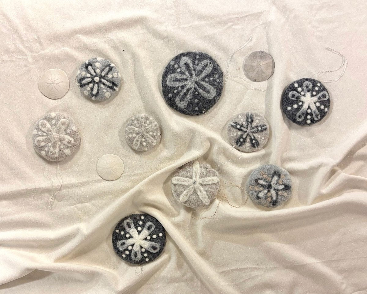 Experience the artistry of needle felting with Halcyon Yarn’s “Needle Felting Class: Sand Dollars with Michelle Provençal (September 5th).” Felted and authentic sand dollars in a variety of sizes are beautifully arranged on a subtly textured fabric backdrop. The needle-felted creations feature intricate star patterns and come in an elegant spectrum from white to gray and black.