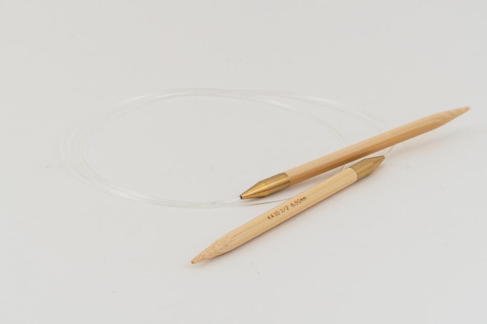 The Circular Bamboo Knitting Needles by Accessories Unlimited (SeeKnit) feature gold-colored ends, a clear flexible cable with a rotating joint, and are shown lying on a white surface.