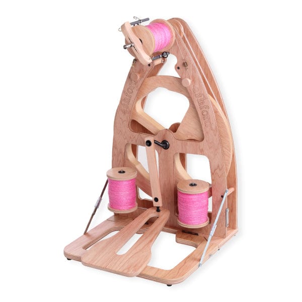 The Ashford Joy 2 Spinning Wheel by Ashford Handicrafts Limited is a compact, upright spinning wheel with two pink yarn bobbins at the base and a spool on top—ideal for portability. Includes a carry bag for easy transport.