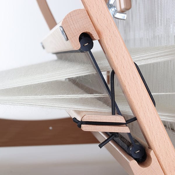 Close-up of an Ashford Handicrafts Limited Table Loom with Overhead Swinging Beater and Shuttle Race, displaying white threads across the frame and tensioning components.