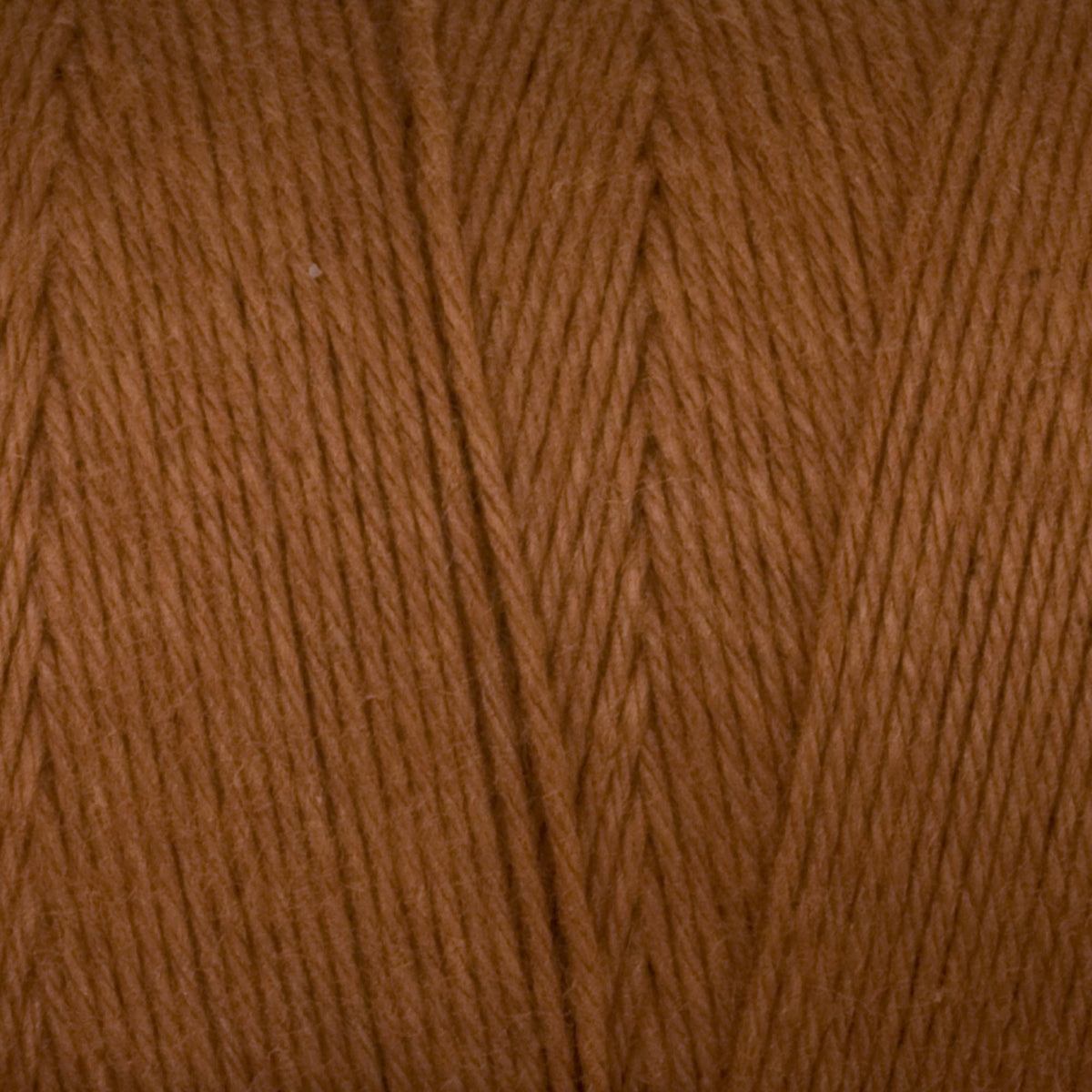 Close-up of Great Northern Weaving’s Cotton Carpet Warp 8/4 highlights the smooth, evenly aligned brown 4-ply cotton fibers, showcasing the soft texture and detail of the tightly wound yarn.