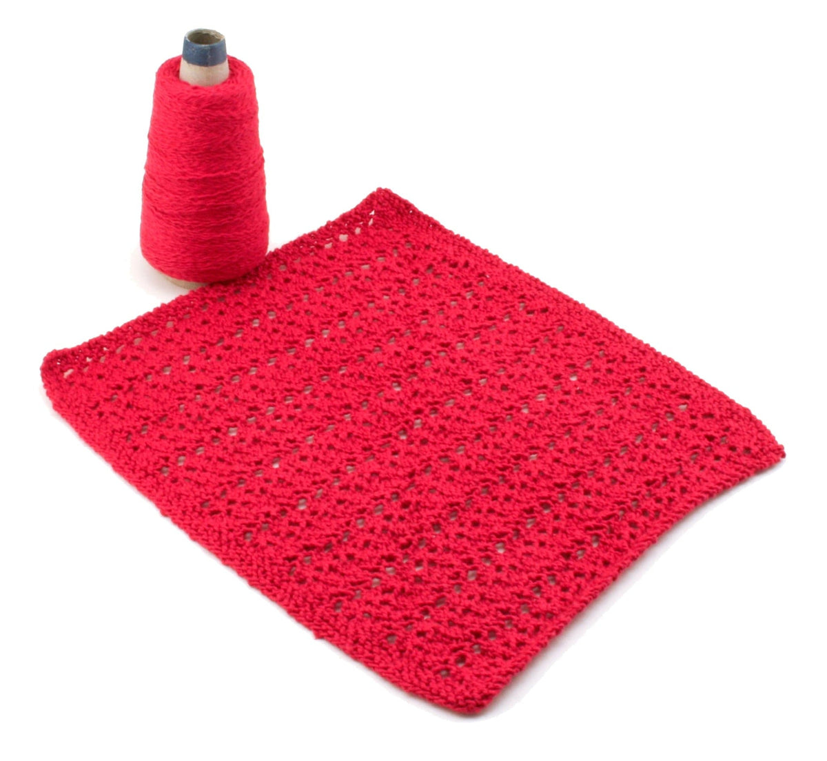 A skein of bright pink Halcyon Yarn Casco Bay Washcloths yarn lies beside a matching crocheted washcloth sample, ideal for testing patterns, both set against a white background.