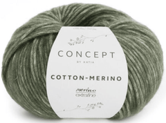 A skein of Katia Cotton-Merino yarn in sage green, combining soft merino and cotton in a chainette structure, is wrapped in a simple white paper band with delicate leaf illustrations and the Katia brand name.