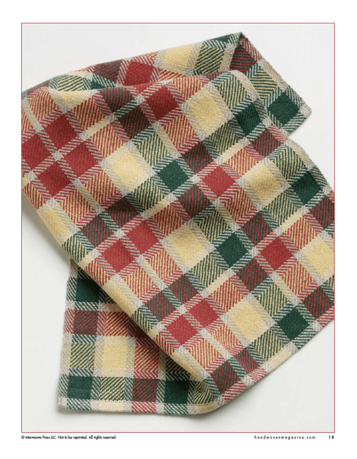 A folded piece of plaid fabric in red, green, yellow, and cream from Long Thread Media’s “Winning Towels from Handwoven's 21st-Century Towel Contest” (eBook printed version), featuring woven herringbone details—perfect towel inspiration.