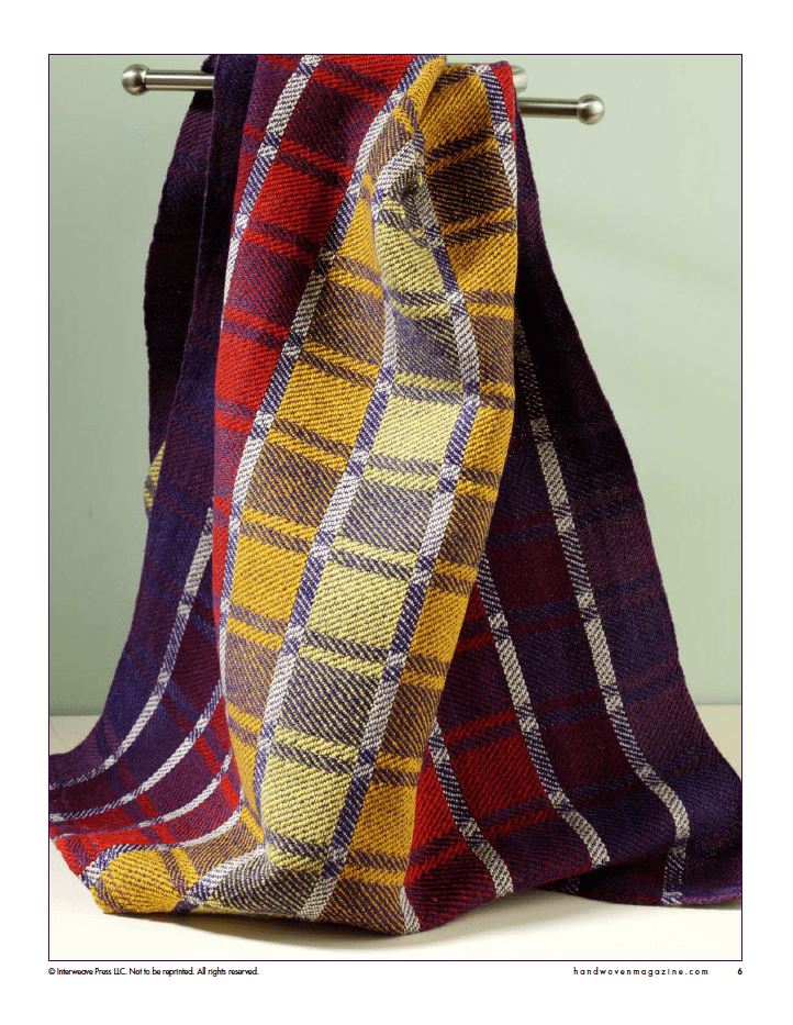 A vibrant plaid towel in red, yellow, and purple hangs on a metal rod—an inspiring project idea from Long Thread Media's Winning Towels from Handwoven's 21st-Century Towel Contest (eBook Printed Version).