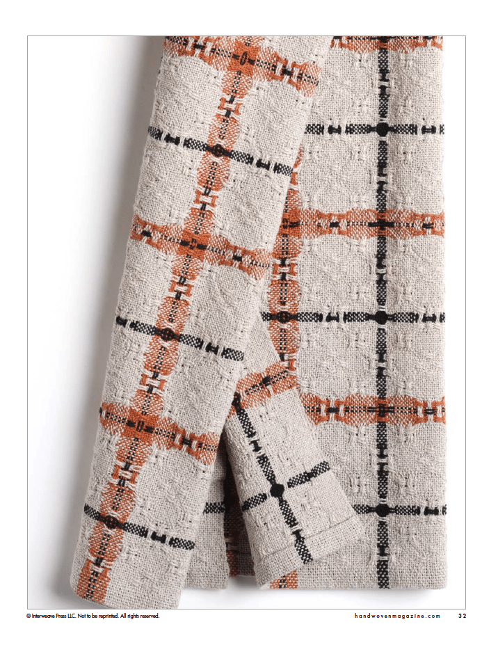A close-up of textured beige fabric with orange and black checkered pattern, ideal inspiration for handwoven towels or your next project from Long Thread Media’s Winning Towels from Handwoven's 21st-Century Towel Contest (eBook Printed Version).