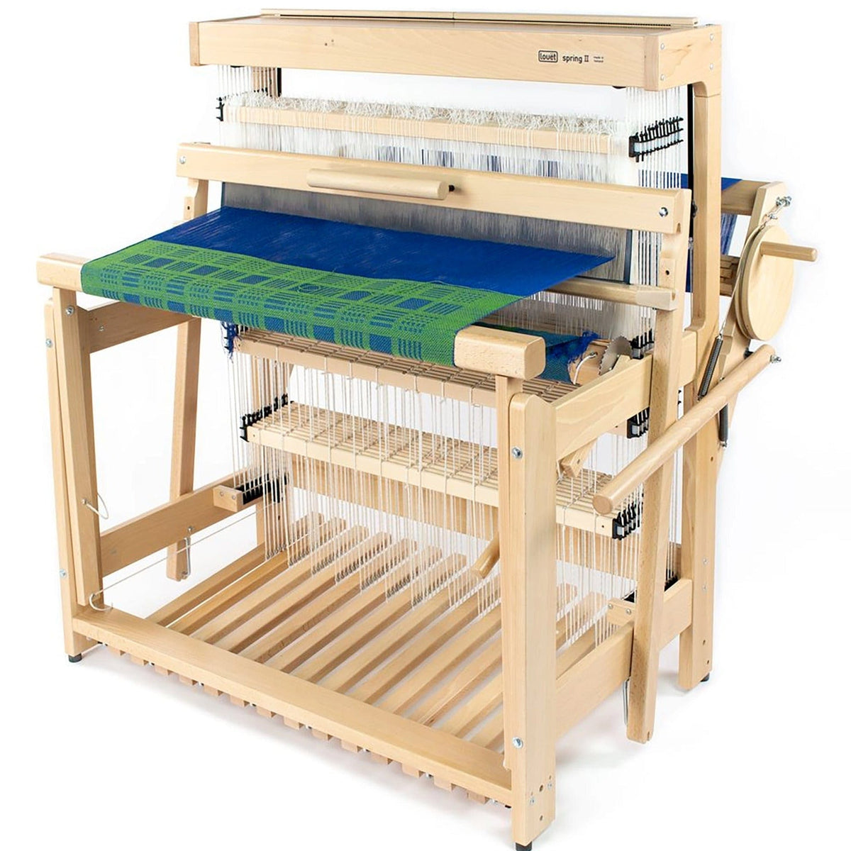 The Louet Inc. Louët Spring 2, an 8 or 12 shaft floor loom, features blue and green fabric partially woven on its countermarche system, with various threads and beams visible throughout the structure for a unique weaving experience.