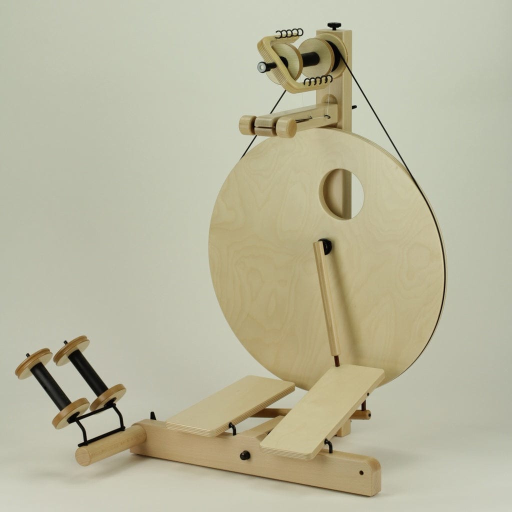 The Louët S10 Concept Double Treadle Irish Tension Spinning Wheel by Louet Inc. is a modern wooden wheel, featuring a large circular design with bulky bobbins ideal for art yarns. Its minimalist design and light wood finish make it perfect for effortlessly spinning yarn or thread.