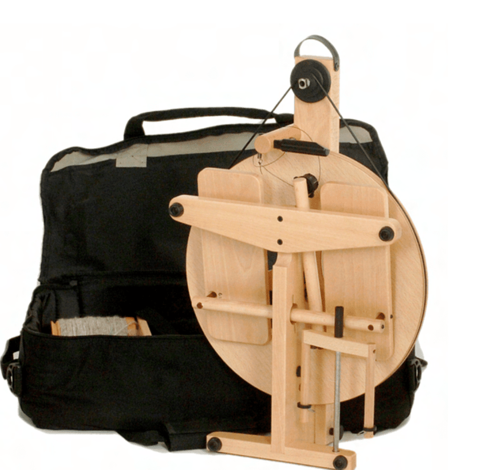 The Louët Victoria Double-Treadle Folding Spinning Wheel, S95 or S96 by Louet Inc. is a modern, wooden spinning wheel featuring a circular section with supporting rods and an adjustable bobbin brake. It stands in front of its open black carrying bag, revealing ample storage space.