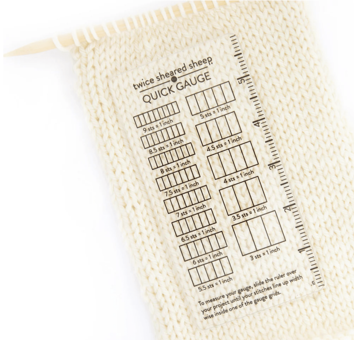 A knitted swatch with the Twice Sheared Sheep Quick Gauge Ruler on top, displaying different stitch and row gauges for knitting. The acrylic ruler tool measures stitches per inch.